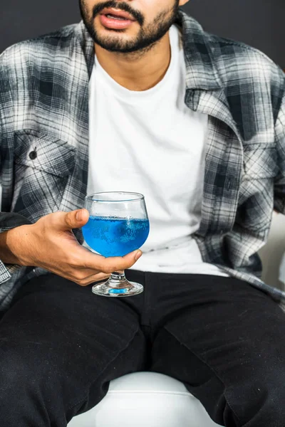 Bu resim, elinde mavi renkli bir içecek tutan bir adamı gösteriyor. Markanızın görselleri için büyüleyici bir sahne yaratıyor.
