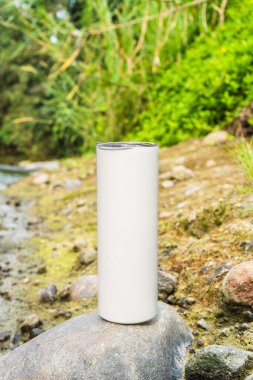 Doğal temalı bir cazibeyle, bu büyüleyici taklit görüntüsü akan bir nehrin yanında beyaz, boş, uzun bir şarap bardağının zarafetini vurgular.