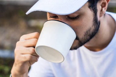 Büyüleyici bir maket görüntüsü, sakallı bir adamın beyaz, boş bir kupayı özgüvenle tanıttığı, karşı konulmaz bir çekiciliği olan bir adamı yansıtır.