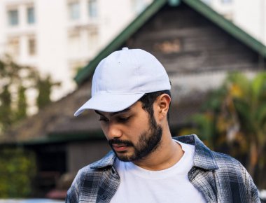 Büyüleyici bir maket görüntüsü beyaz boş bir şapka takan genç bir adamın cazibesini sergiliyor.