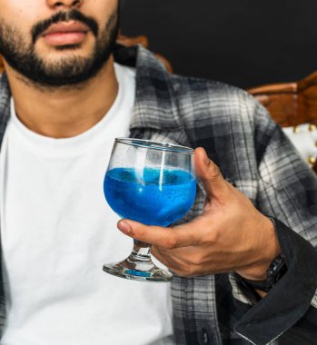 Şarabın cazibesini kucakla genç bir adam bu büyüleyici sahnede içkisini kendinden emin bir şekilde gösteriyor.