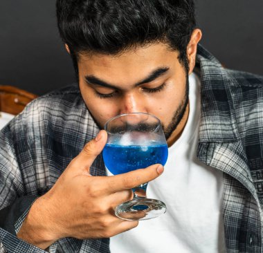 Biraz özgüvenle, bir maket görüntüsü sunar genç bir adam şarabının tadını çıkarırken.