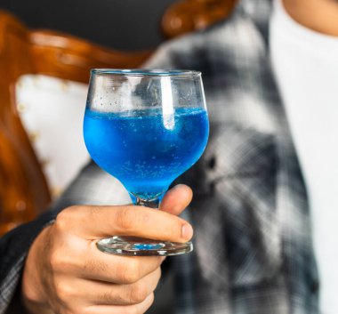 Biraz karizmayla, bir maket görüntüsü sunar. Şarap içen genç bir adam.