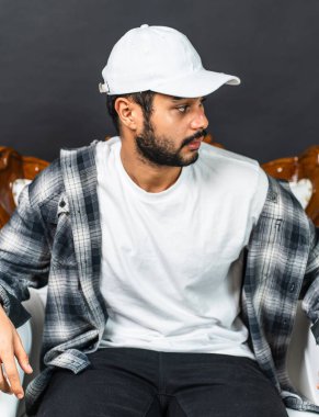 Bu büyüleyici görüntüde beyaz bir gömlek ve şapka giyen genç bir adamın ebedi cazibesini kucaklayın.