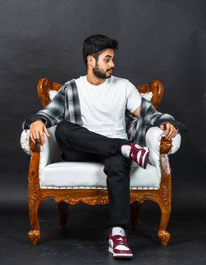 Çabasız bir şekilde şık, genç adamın rahat zarafetini gösteren bir resim, beyaz boş bir gömlekle basit bir poz vermiş.