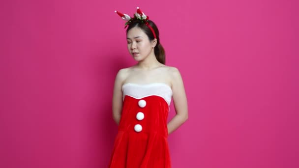 亚洲女人穿着圣诞主题的衣服 背带粉色背景 摆出一副姿势的形象 — 图库视频影像