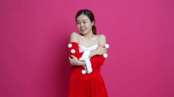 背面にピンクの背景を持つ凍結ポーズをすることをテーマにしたクリスマスを着たアジアの女性の映像 — ストック動画