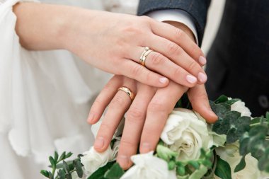 Hands of the bride and groom with wedding rings on a bouquet. The wedding ceremony. Love. Wedding rings