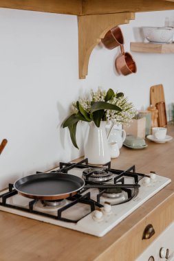 İskandinav tarzı mutfak manzarası beyaz tonlarda, soba, lavabo ve raflarla. Satılık lüks bir daire. Yemek pişirmek için rahat bir yer.