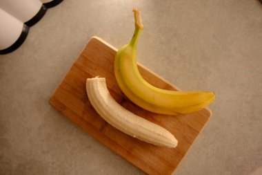 Olgun sarı muz, soyulmuş muz, mutfak masasında olgun muz dilimleri.