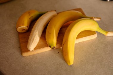 Olgun sarı muz, soyulmuş muz, mutfak masasında olgun muz dilimleri.