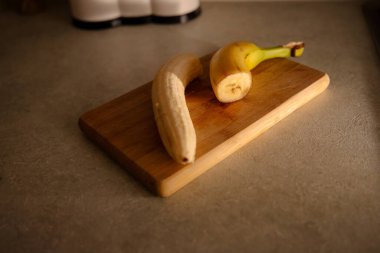 Olgun sarı muz, soyulmuş muz, mutfak masasında olgun muz dilimleri.