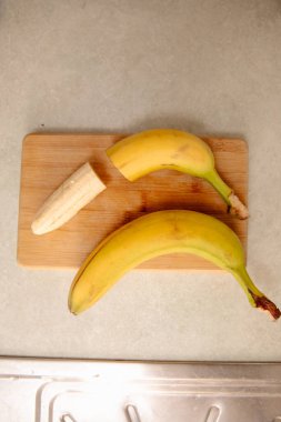Olgun sarı muz, soyulmuş muz, mutfak masasında olgun muz dilimleri.
