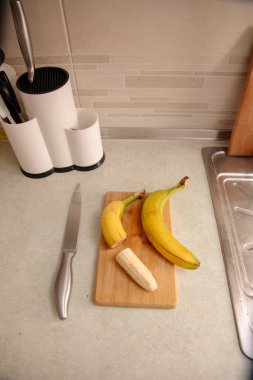 Olgun sarı muz, soyulmuş muz, mutfak masasında olgun muz dilimleri.