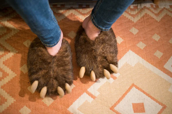 Feet with bear claws slippers. Seen from above. Interior