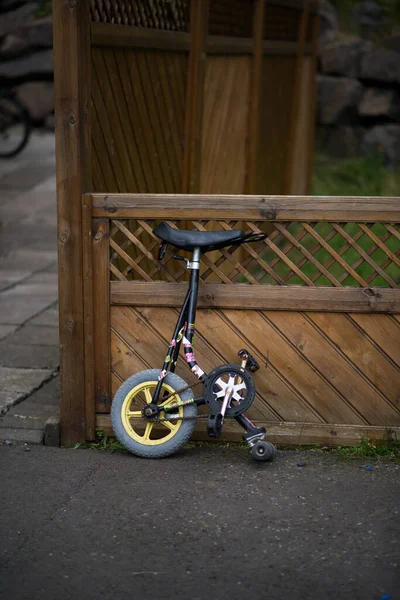 Half of a bicycle in a backyard. One wheel.