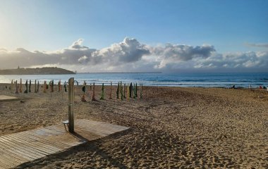 San Lorenzo sahilinde gün batımı, Gijon. Kapalı şemsiyeler. Ufukta bulutlar