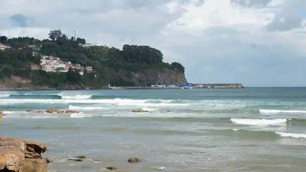 Colunga 'daki La Griega plajından panoramik manzara. Lastres, huzurlu bir balıkçı köyü, uzaktan görülebilir. Asturias, İspanya