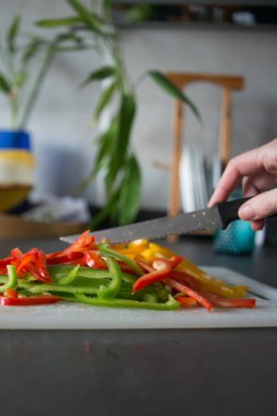 Evcil bir mutfakta bıçakla sebze doğrayan tanınmamış bir kadın eli.