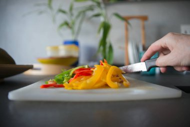 Evcil bir mutfakta bıçakla sebze doğrayan tanınmamış bir kadın eli.