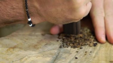 Mutfaktaki ahşap tahtada havan topuyla mis kokulu baharatları ezen bir adamın eli. Şef akşam yemeği için çorbanın içine lezzet katar.