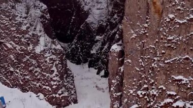 Brown rock formations covered with white snow in cold winter. Scenic nature and landscapes of giant Caucasus mountains aerial view