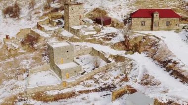 Bulutlu kış gününde Kafkasya dağlarının karlı yamaçlarına tuğla evler inşa edildi. İskoçya 'da beyaz kar manzaralı bir yerleşim yeri.