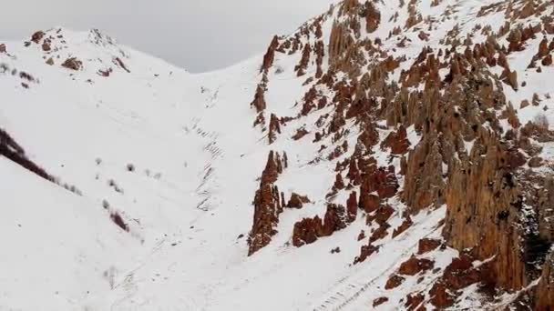 巨大的高加索山脉峡谷的斜坡上形成了岩石 冬季乌云密布的空中俯瞰着白雪覆盖着高地 — 图库视频影像