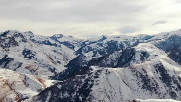 在白云笼罩的天空下 白雪覆盖着高加索山口周围的岩石山峰 冬日空中景观下的高原风景自然 — 图库视频影像