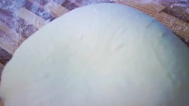 Gevşek beyaz hamurlar un ahşap masa ile serpiştirilir. Pastanede lezzetli ekmek ve çörekler pişirmek. Mutfaktaki makroda taze yiyecek.