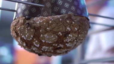 Beyaz serpiştirilmiş sıcak paskalya pastası raftaki ince şişler üzerinde baş aşağı asılı duruyor. Lezzetli tatil hamur işleri bulanık arka planda fırın makrolarında serindir.