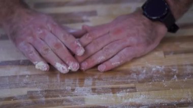 Erkek fırıncı elleriyle hamur toplar. Fırının ahşap masasında el yapımı çörek yapıyorlar. Profesyonel aşçı mutfakta yakın plan aşçıdır.
