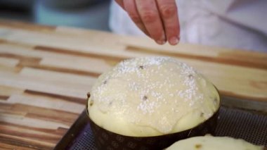 Erkek şekerleme serpme Hindistan cevizi talaşı yuvarlak çiğ hamurlu pasta ve kuru üzüm. Paskalya pastalarını kağıt pişirme formunda süslemek.