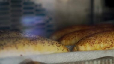 Domates soslu uzun çörekler fırında tepside pişiyor. Fırında taze hamur işleri pişiriyorum. Bulanık arkaplanda tuzlu un ürünleri