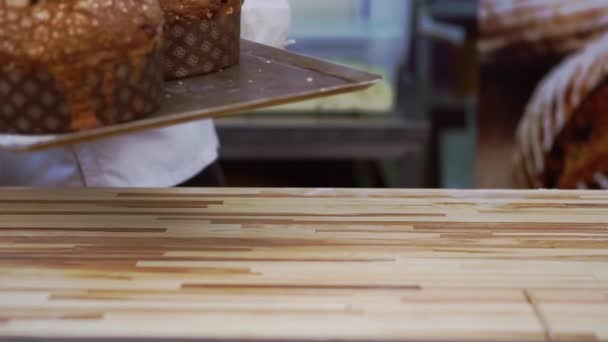 紙の形でおいしいホットイースターケーキ ミトンとホワイトエプロンのベイカーは 新鮮なペストリーを取り出し 木製のテーブルの上にトレイを閉じます — ストック動画