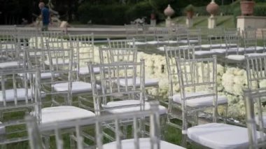 Düğün kutlaması için açık havada çiçek buketleriyle süslenmiş. Otel ve restoran kompleksindeki düğün yerinde beyaz sandalyeler