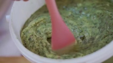 Şekerci spatulayla krema karıştırıyor. Plastik kabın içindeki lezzetli yemek için tatlı malzeme. Pastanede yakın plan pişirme işlemi