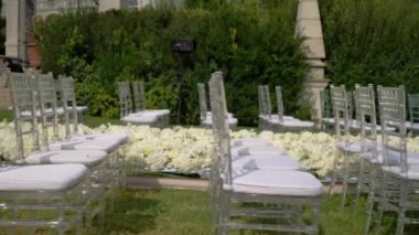Düğün kutlaması için açık havada çiçek buketleriyle süslenmiş. Otel ve restoran kompleksindeki düğün yerinde beyaz sandalyeler