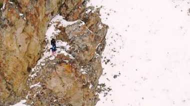 Men climbers climb large rocky formation in Caucasus mountains on winter day. Tourist enjoys extreme activity in highland during trip aerial view