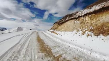 Kafkasya dağlarında bulutlu gökyüzünün altında, karlı bir yolda araba sürüyor. Kuzey İskoçya 'da, araçtan kış günü manzaralı maceralı bir yolculuk.