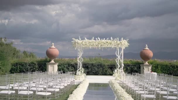 通路と装飾された椅子に白い花のアーチと屋外の結婚式会場 空に対する芝生の上で結婚式を祝うための高価な場所 — ストック動画