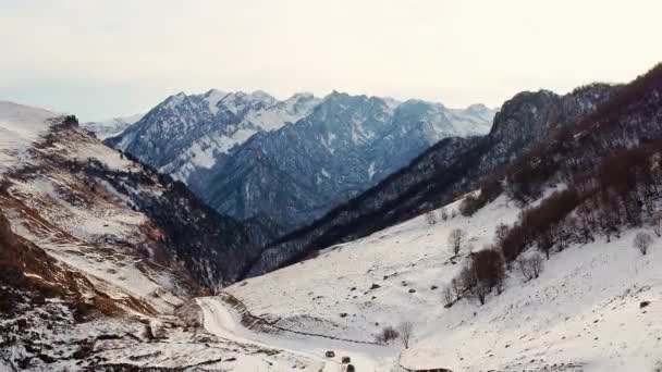 在多云的冬日 汽车在雪地的大峡谷中蜿蜒前行 宏伟的高加索山口上覆盖着雪白的空中景观 — 图库视频影像