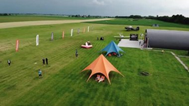 Skydiver yarışmalarda uçurtma uçurmaya hazırlanan insanların üzerine iniyor. İnsanlar hangar yakınlarındaki oyunlara başlamadan önce son hazırlıklarını tamamlıyorlar.