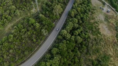 Serpentine asfalt yolu yeşil ağaçların arasında kırsala çıkar. Arabalar ağaçlarda ve yüksek voltajlı direklerde gizlenmiş küçük çiftliklerin yanından geçiyor.