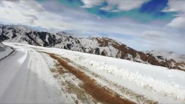 Kafkasya dağlarında bulutlu gökyüzünün altında, karlı bir yolda araba sürüyor. Kuzey İskoçya 'da, araçtan kış günü manzaralı maceralı bir yolculuk.