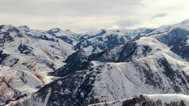 白亜の山の周りの岩のピークは 曇りの空の下で白い雪で覆われたパス 冬の日の空中風景の高原の風景 — ストック動画