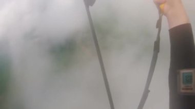 Siyah tulumlu paraşütçü pilotlar kalın beyaz bulutlar arasında. İnsan paraşüt kullanırken paraşütü kontrol eder. Paraşütçü manzaranın ilk bakış açısını sever