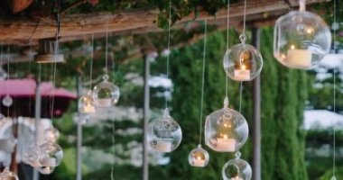 Tavandan sarkan şeffaf topların içinde mumlar olan düğün dekorasyonları. Düğün hazırlıkları ve restoranda kutlama.