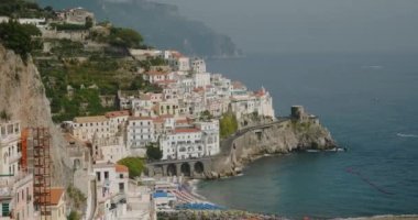 Antik binaları ve dağ eteğinde sallanan yolları olan turistik Amalfi. Gök mavisi deniz suyu kayalıkları eski kalelerle yıkar.