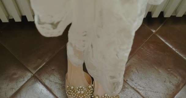 酒店房间里的白色婚纱下 露出装饰宝石和珍珠珠子的鞋子 豪华婚礼的准备 — 图库视频影像